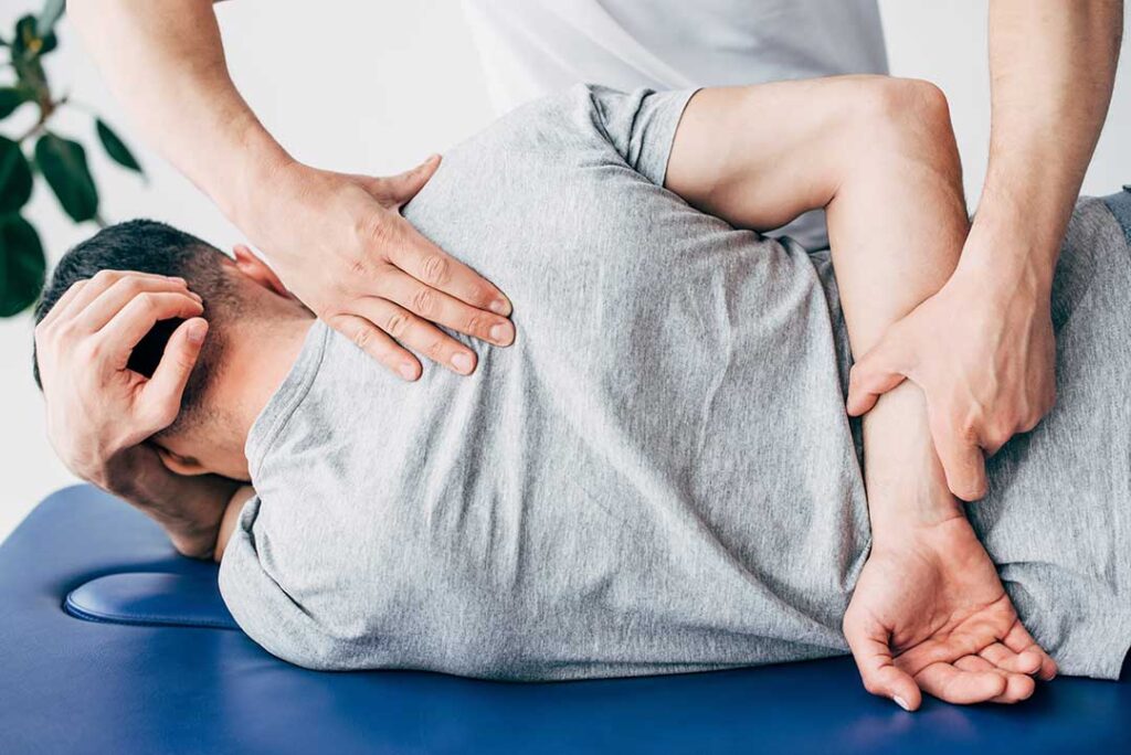 A pregnant woman sitting on a couch using a pillow for back support while doing gentle stretches.