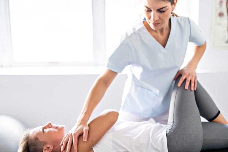 Clinician uses a smooth metal tool on a patient’s forearm during soft-tissue treatment.